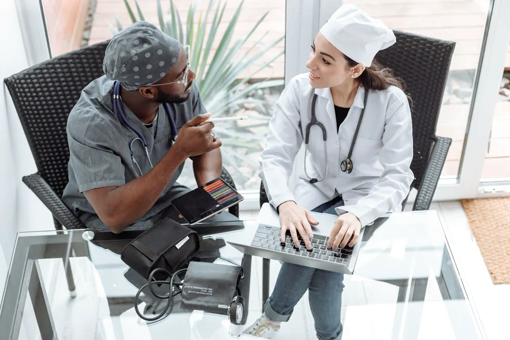 Deux médecins échangent autour d’un ordinateur portable.