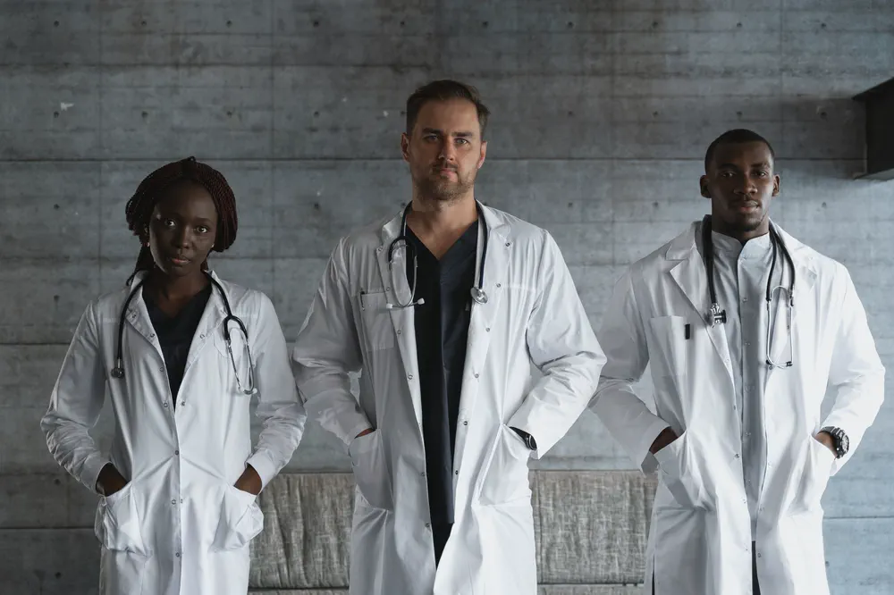 Trois médecins en blouse blanche réunis dans un cabinet de groupe.